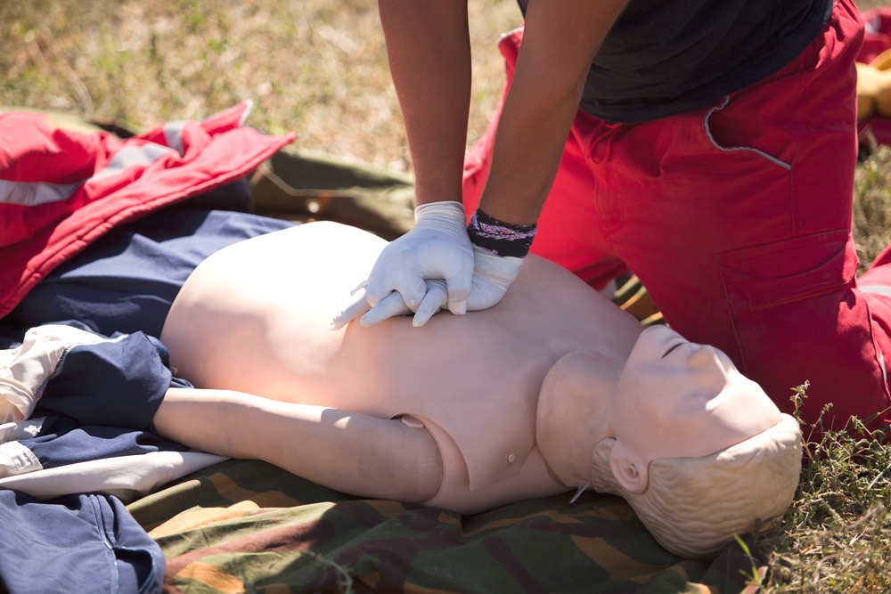 person practicing CPR on a doll