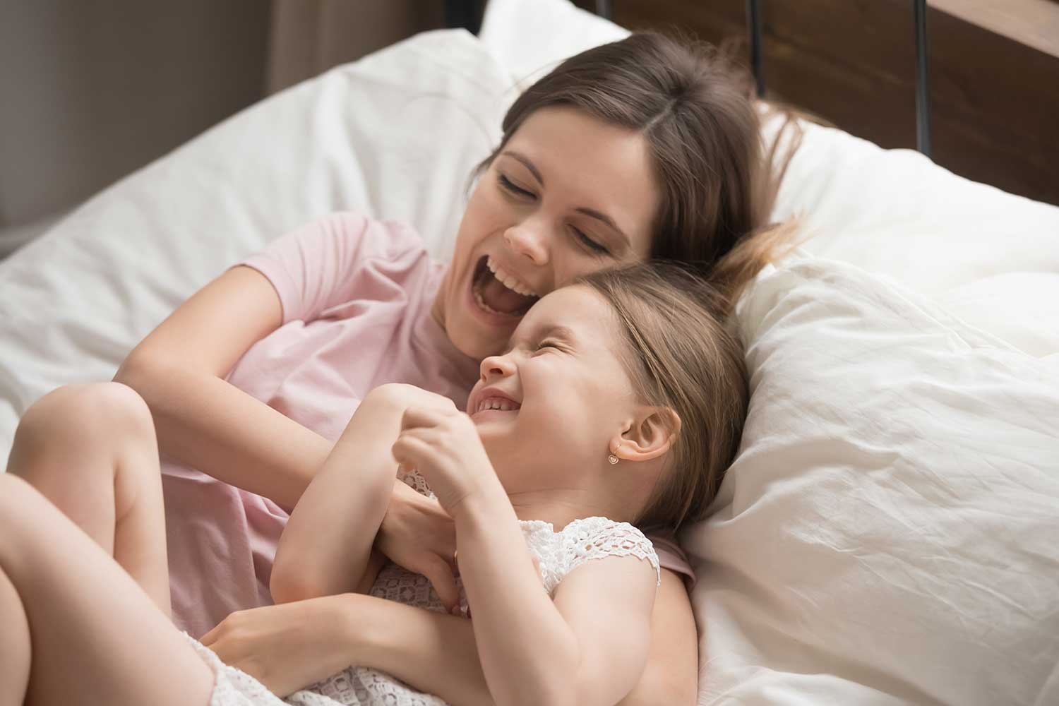 woman and daughter playing in bed