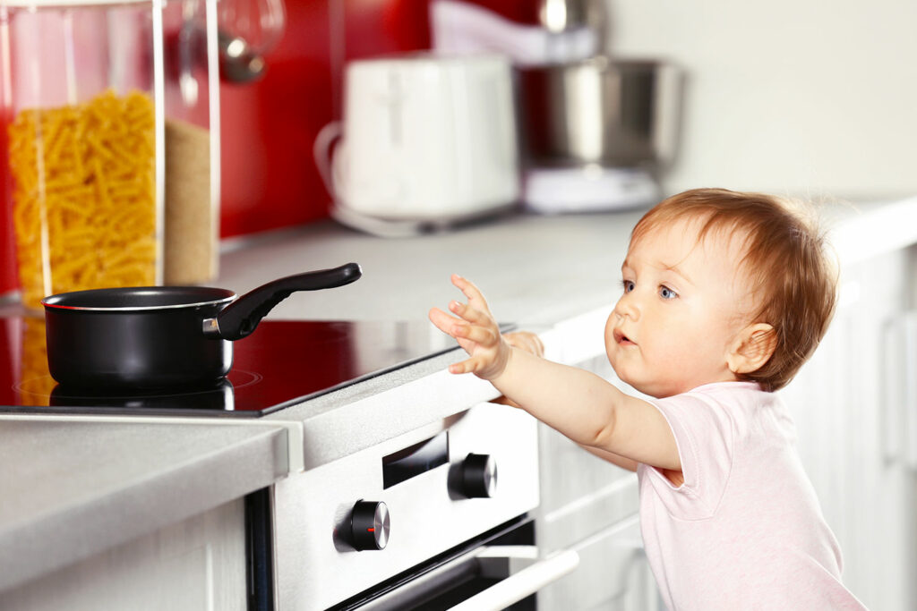 child reaching for pot on the stove