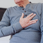 Elderly man clutching chest, possibly experiencing pain in chest.