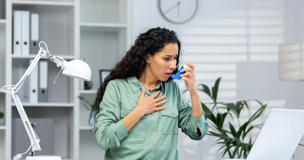 Woman struggling to breathe while coughing and using inhaler