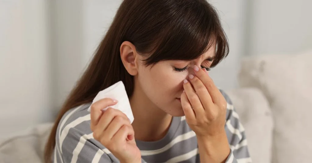 Woman pressing nose bridge while experiencing sinus pressure symptoms.