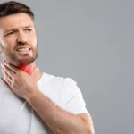 Man touching painful throat area showing laryngitis symptoms.